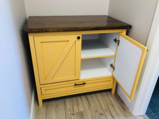 Yellow cabinet with a wooden top, an open door, and two inner shelves.