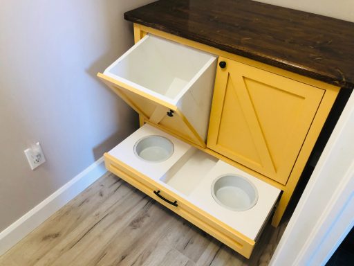 Storage cabinet with a yellow exterior, featuring a top drawer and two bowl-shaped compartments.