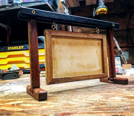 A wooden frame on a stand, hanging empty in a workshop setting.
