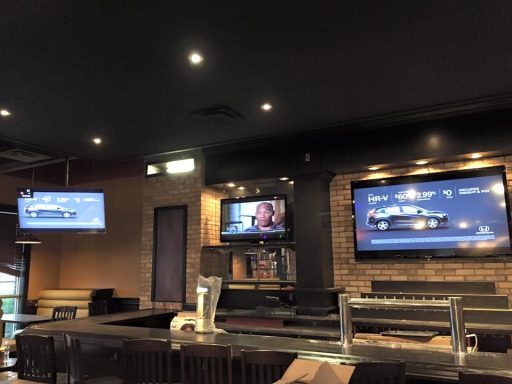 Interior of a bar with multiple TVs showing sports and a wooden counter.