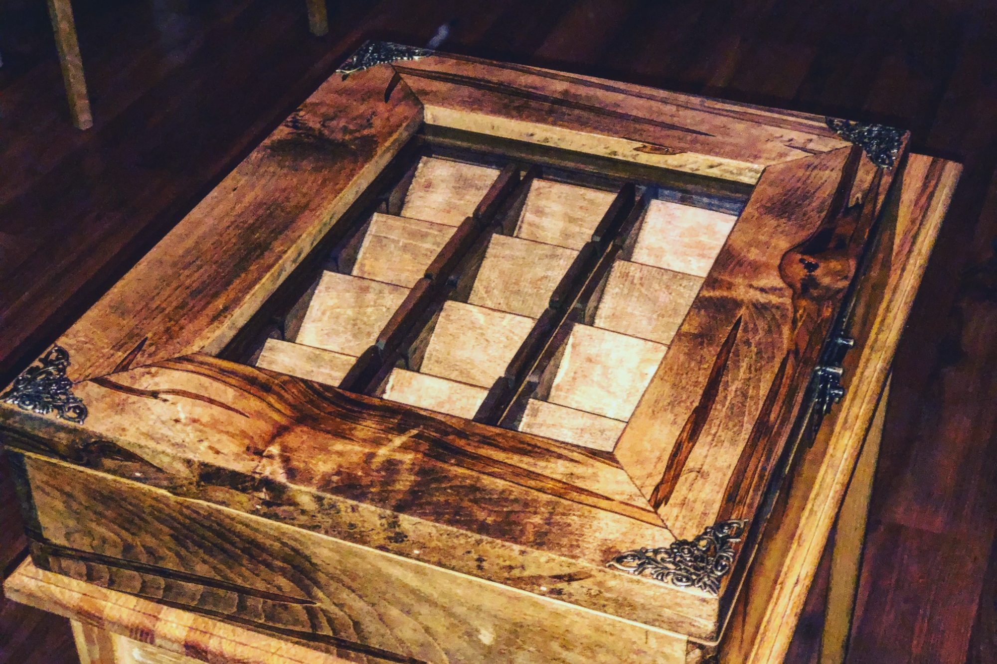 Wooden box with a glass top and multiple wooden compartments inside.