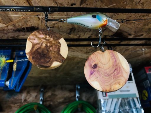 Wooden disks with intricate patterns and a colorful fishing lure hang from hooks.