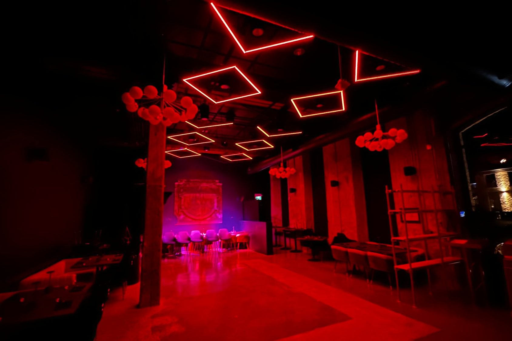Dimly lit venue with red LED lighting, modern decor, and seating areas.